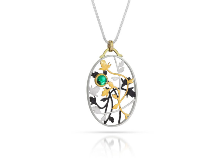 Oval pendant with silver, black, and gold roses and vines with emerald
