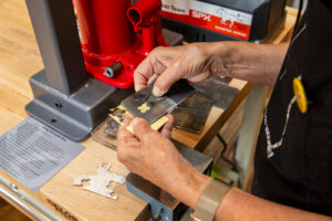 artist's hands holding metalsmithing tools